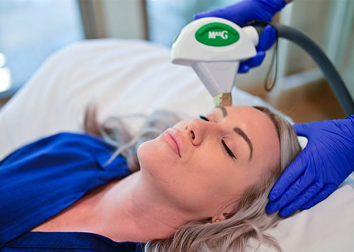 A woman receiving a facial treatment with a handheld device in a medical spa setting. Saxon MD