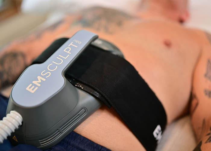 An emsculpt device attached to a person's abdomen, focusing on muscle stimulation treatment. Saxon MD