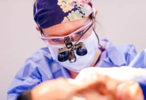 Dr. Sarah Saxon, Austin facial plastic surgeon, operating with surgical loupes during a deep plane facelift